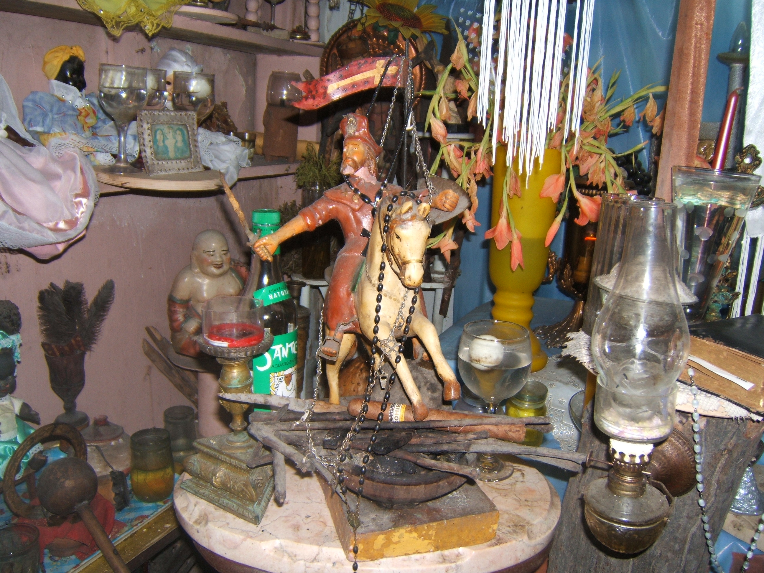 Figure 6. Santiago astride a horse, draped in a rosary and a necklace adorned with metal tools. Iron “warrior” implements and other offerings are arrayed before him. Santiago de Cuba, August 2008. Photograph by author.